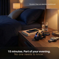 Black shockwave therapy device on nightstand beside a glass of water